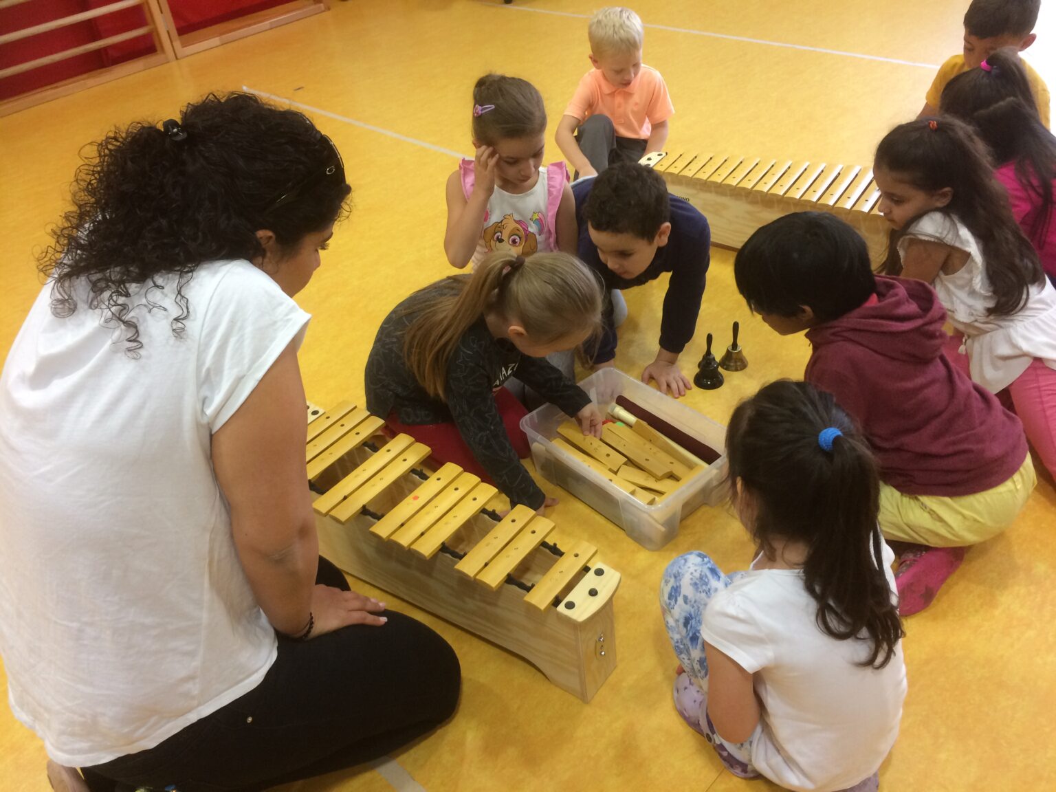 Foto von Kindern und Erzieherin vor einem Xylophon in einer KiTa